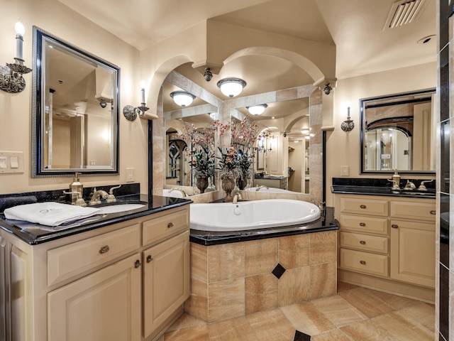 bathroom featuring vanity, tiled tub, and tile patterned flooring