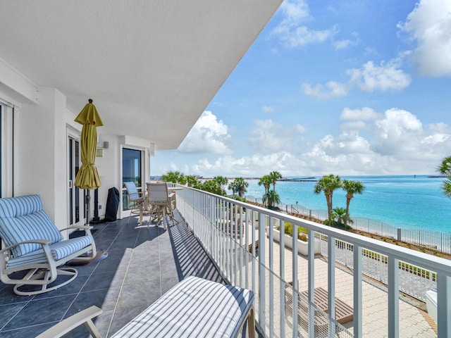 balcony with a water view and a view of the beach