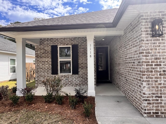 property entrance featuring brick siding and roof with shingles