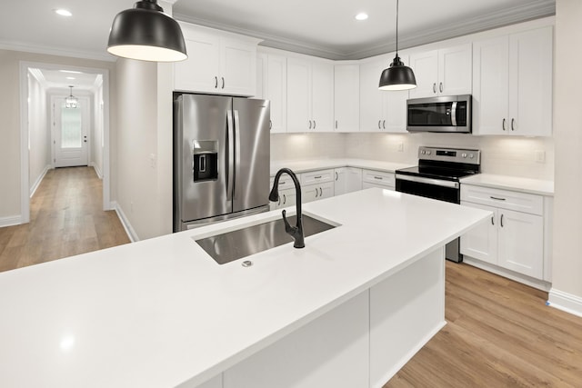 kitchen featuring decorative backsplash, appliances with stainless steel finishes, crown molding, light wood-style floors, and a sink