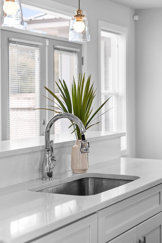 details with hanging light fixtures, sink, and white cabinets