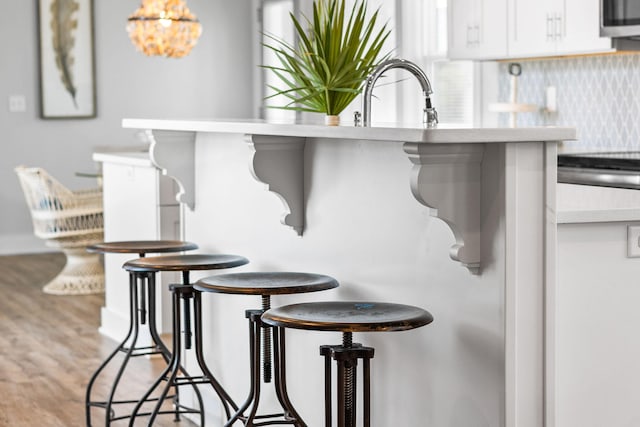 room details featuring hardwood / wood-style floors, decorative backsplash, and sink