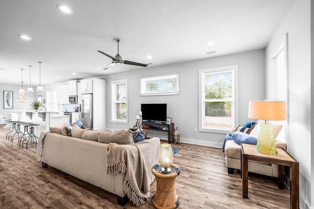 living room featuring ceiling fan, a healthy amount of sunlight, and wood-type flooring