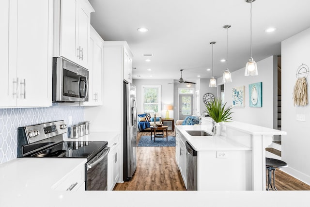 kitchen featuring pendant lighting, white cabinetry, a kitchen bar, stainless steel appliances, and a center island with sink