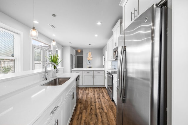 kitchen with pendant lighting, sink, appliances with stainless steel finishes, white cabinetry, and kitchen peninsula