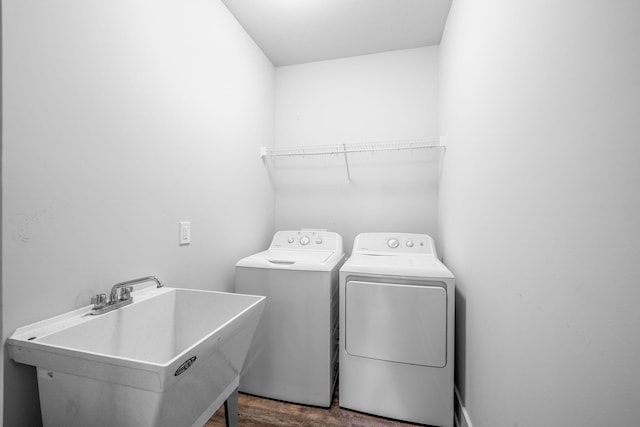 clothes washing area featuring sink, hardwood / wood-style floors, and washing machine and clothes dryer