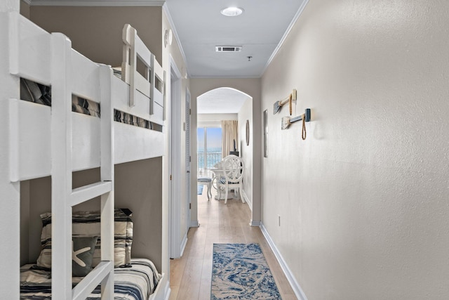 corridor featuring ornamental molding and light wood-type flooring