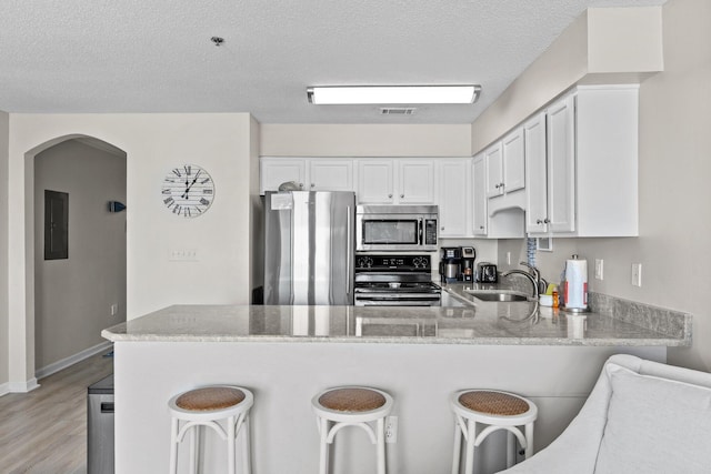 kitchen with sink, kitchen peninsula, white cabinets, and appliances with stainless steel finishes