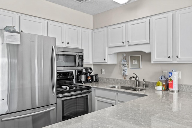 kitchen with white cabinetry, sink, stainless steel appliances, light stone countertops, and a textured ceiling