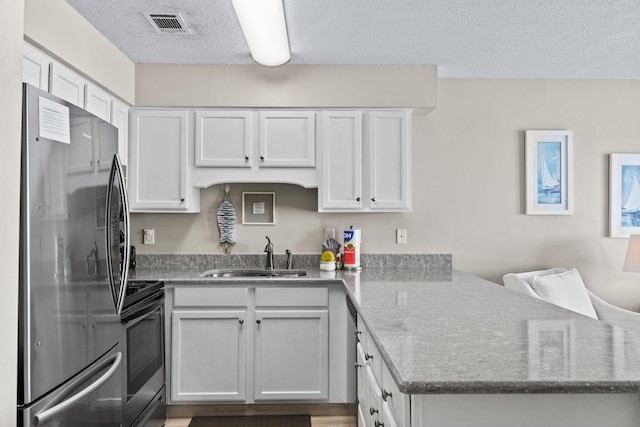 kitchen with sink, white cabinetry, a textured ceiling, kitchen peninsula, and stainless steel appliances