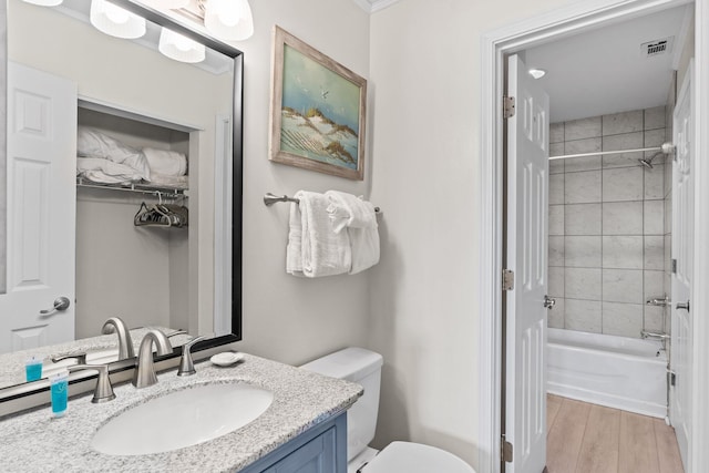 full bathroom featuring tiled shower / bath combo, wood-type flooring, vanity, and toilet