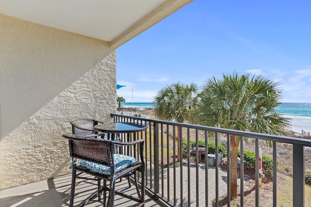 balcony with a water view and a view of the beach