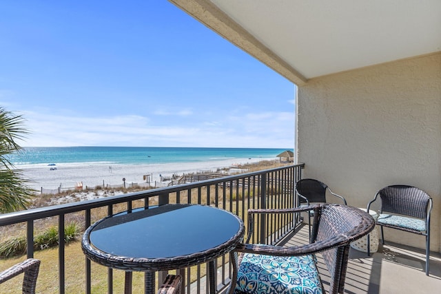 balcony with a water view and a view of the beach