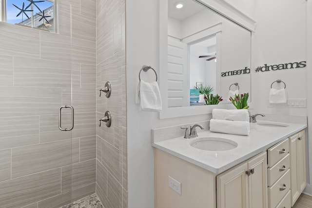 full bathroom featuring double vanity, a shower stall, ceiling fan, and a sink