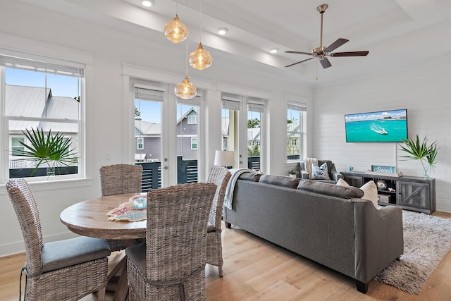 dining room featuring plenty of natural light, a tray ceiling, and light wood-type flooring