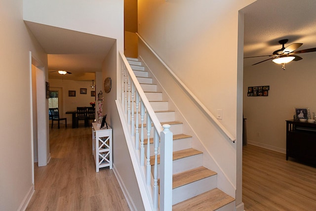 stairs featuring hardwood / wood-style flooring and ceiling fan