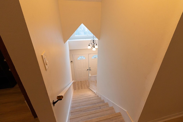 stairway featuring an inviting chandelier, wood-type flooring, and a towering ceiling