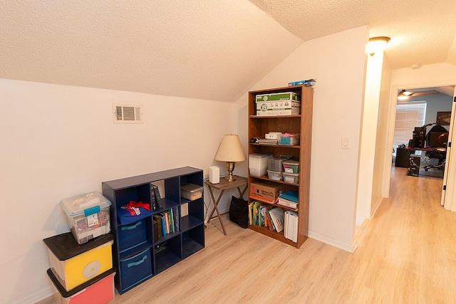 interior space featuring light hardwood / wood-style flooring, a textured ceiling, and lofted ceiling