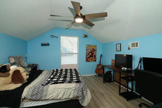 bedroom with light wood-type flooring, vaulted ceiling, a textured ceiling, and ceiling fan