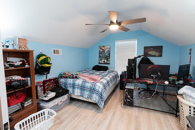 bedroom featuring hardwood / wood-style flooring, vaulted ceiling, and a textured ceiling