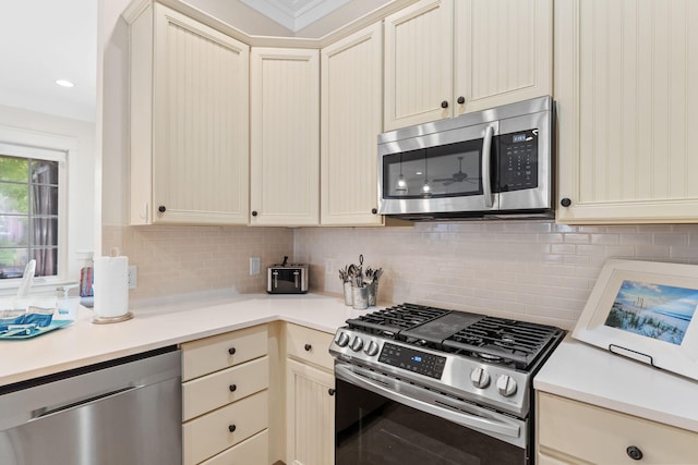 kitchen featuring tasteful backsplash, cream cabinets, and appliances with stainless steel finishes