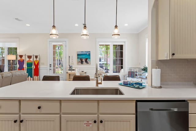 kitchen with sink, dishwasher, hanging light fixtures, cream cabinets, and ornamental molding