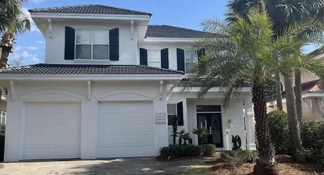 view of front facade with driveway, a tiled roof, and stucco siding