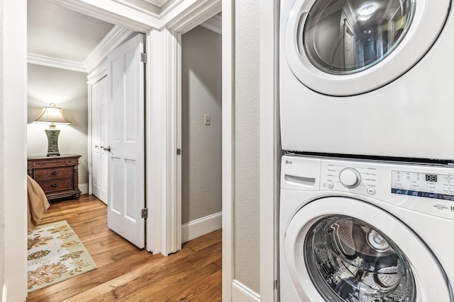 clothes washing area featuring stacked washer and dryer, light hardwood / wood-style flooring, and ornamental molding