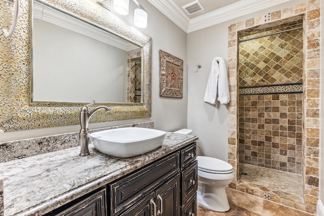 bathroom with crown molding, a tile shower, vanity, and toilet