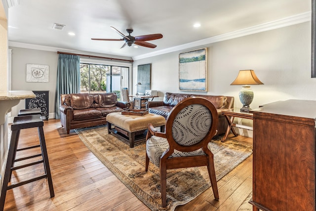 living room featuring crown molding, light hardwood / wood-style floors, and ceiling fan