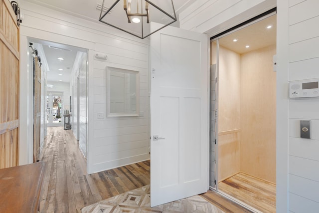 corridor with wooden walls, elevator, and a barn door