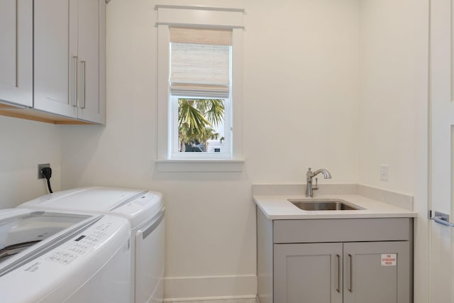 clothes washing area featuring sink, washer and clothes dryer, and cabinets