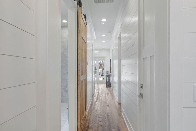 corridor with hardwood / wood-style flooring and a barn door