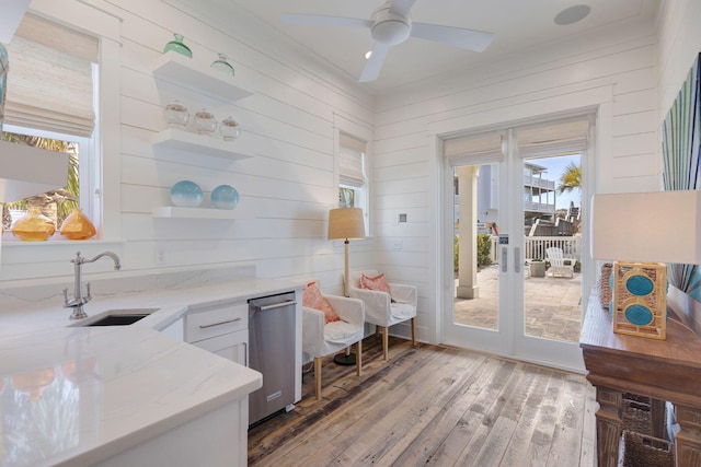 kitchen with sink, ceiling fan, white cabinetry, hardwood / wood-style floors, and light stone counters