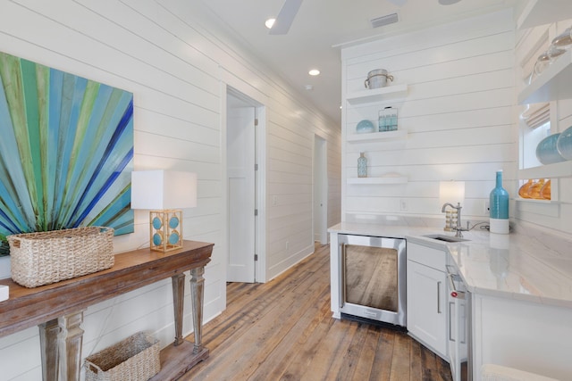 interior space with white cabinetry, sink, fridge, light stone countertops, and light hardwood / wood-style flooring