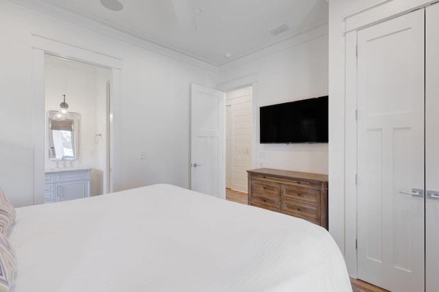 bedroom featuring crown molding, connected bathroom, and light hardwood / wood-style floors