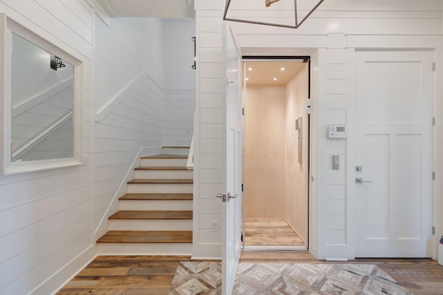 stairs featuring elevator and hardwood / wood-style floors