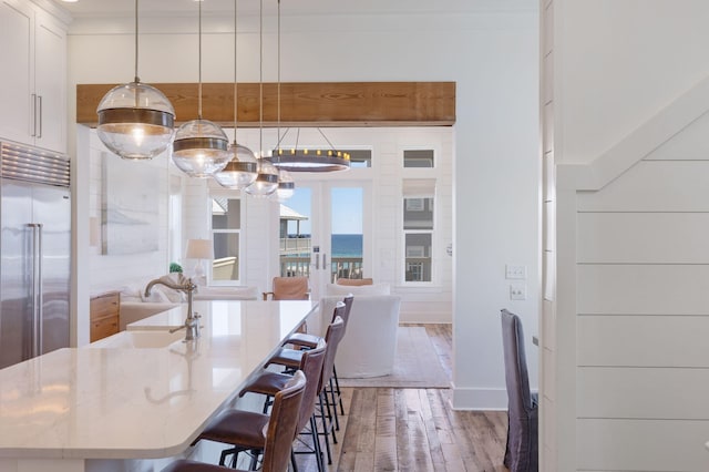 unfurnished dining area with hardwood / wood-style flooring, a water view, sink, and french doors