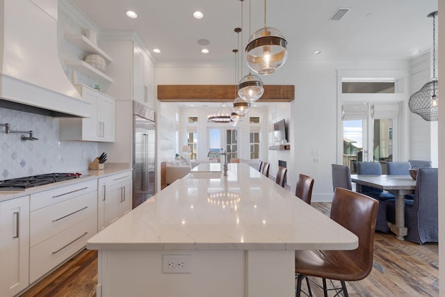 kitchen featuring a kitchen island with sink and white cabinets