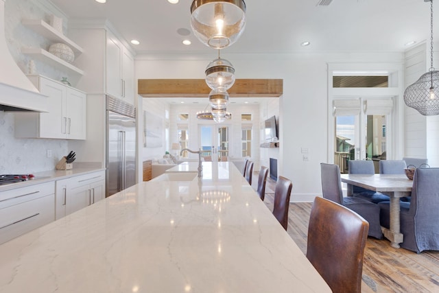 dining space featuring french doors, crown molding, sink, and light hardwood / wood-style flooring