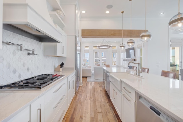 kitchen with stainless steel appliances, premium range hood, sink, and white cabinets