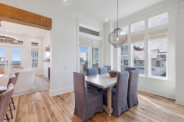 dining area featuring french doors, crown molding, light hardwood / wood-style floors, and a notable chandelier