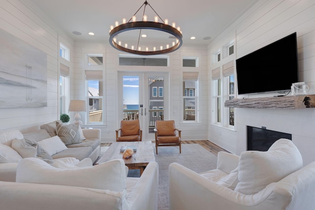 living room with a notable chandelier, wood-type flooring, ornamental molding, and french doors