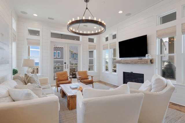 living room featuring french doors, crown molding, light hardwood / wood-style flooring, and a notable chandelier