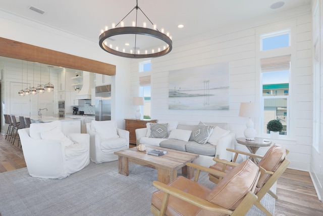 living room featuring an inviting chandelier, wood-type flooring, and a healthy amount of sunlight