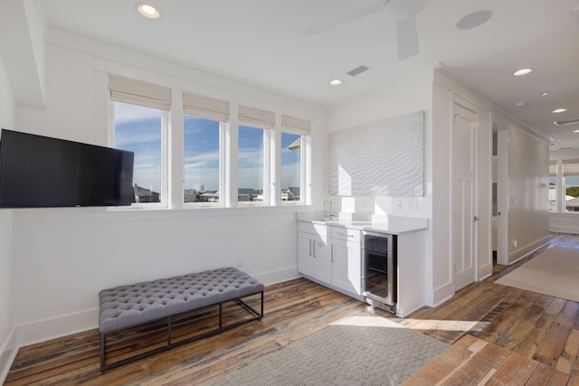 bar featuring wine cooler, sink, hardwood / wood-style flooring, ceiling fan, and white cabinets