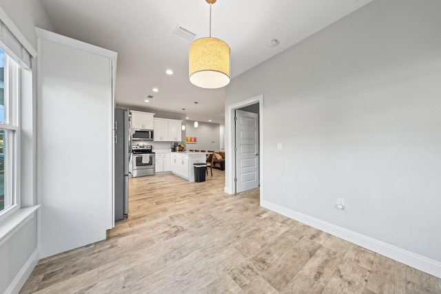 kitchen with stainless steel appliances, white cabinetry, hanging light fixtures, and plenty of natural light