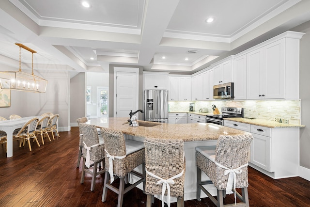 kitchen featuring appliances with stainless steel finishes, sink, white cabinets, light stone counters, and a center island with sink