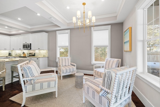 living room with crown molding, a tray ceiling, a chandelier, and a wealth of natural light