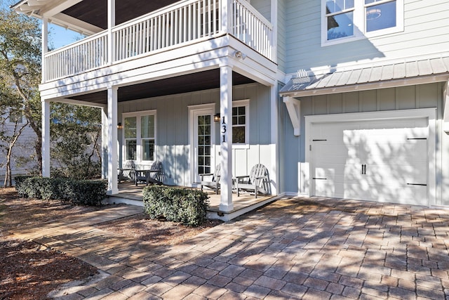 doorway to property with a garage, a balcony, and covered porch